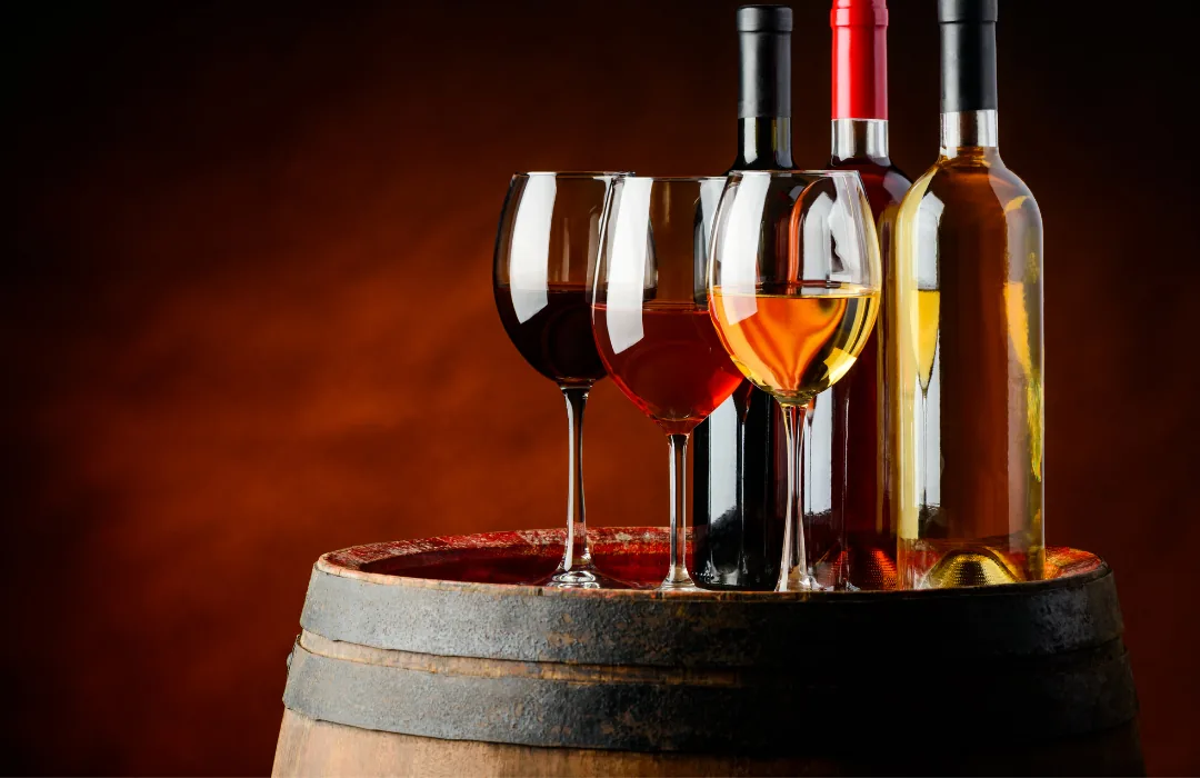 Glasses of white, rosé and red wine beside bottles